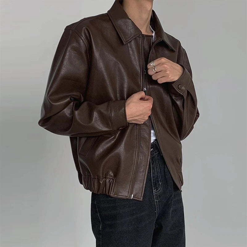 Model zipping up a brown boxy faux leather jacket with point collar