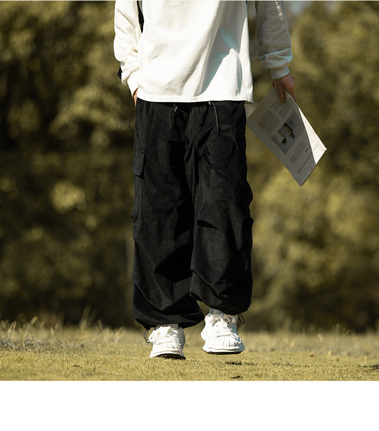 Black corduroy cargo pants with drawstring cuffs pulled in, front view