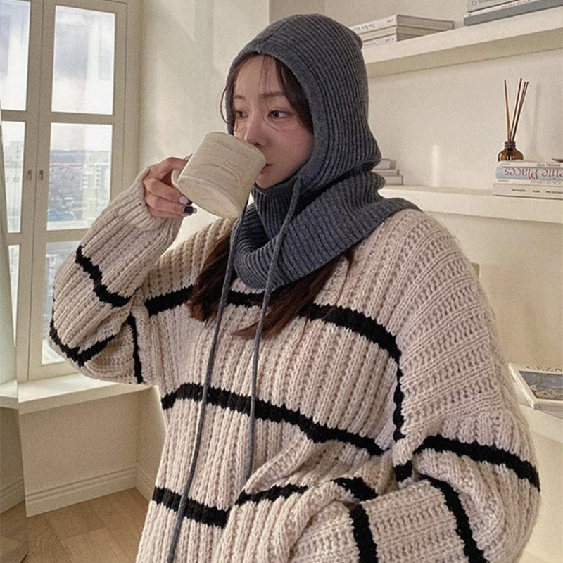 Model in gray ribbed knit balaclava with drawstring ties, three-quarter view