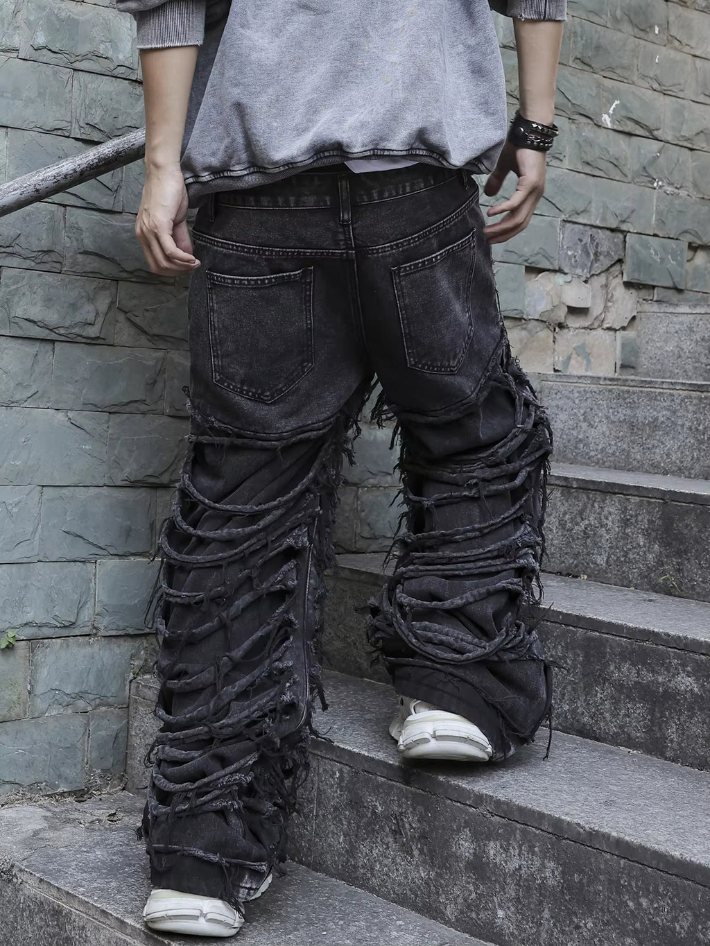 Men's black jeans. With a design of (ripped holes) and tassels. In a street trend style.