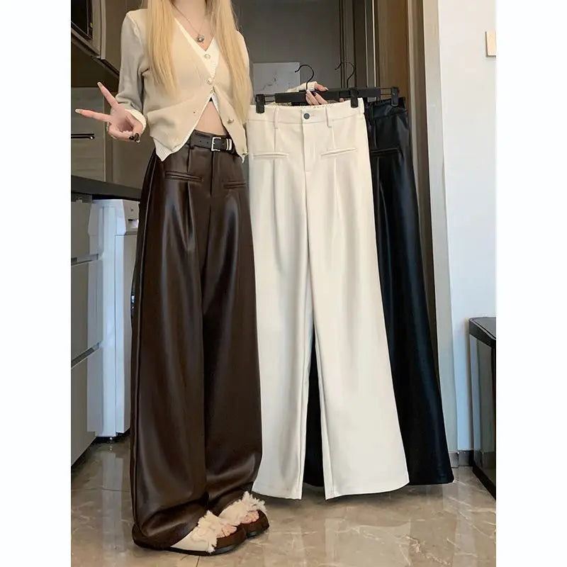 Brown faux leather wide-leg pants worn with a cream cardigan, black and cream pairs on a hanger beside them