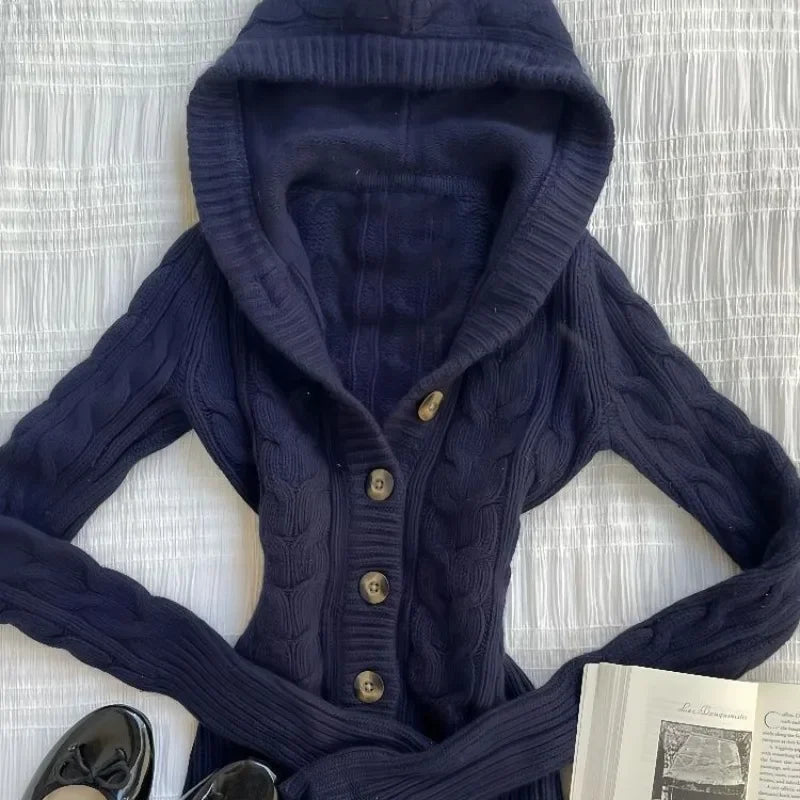 Navy cable-knit cardigan laid flat, close-up of the ribbed hood edge and buttons
