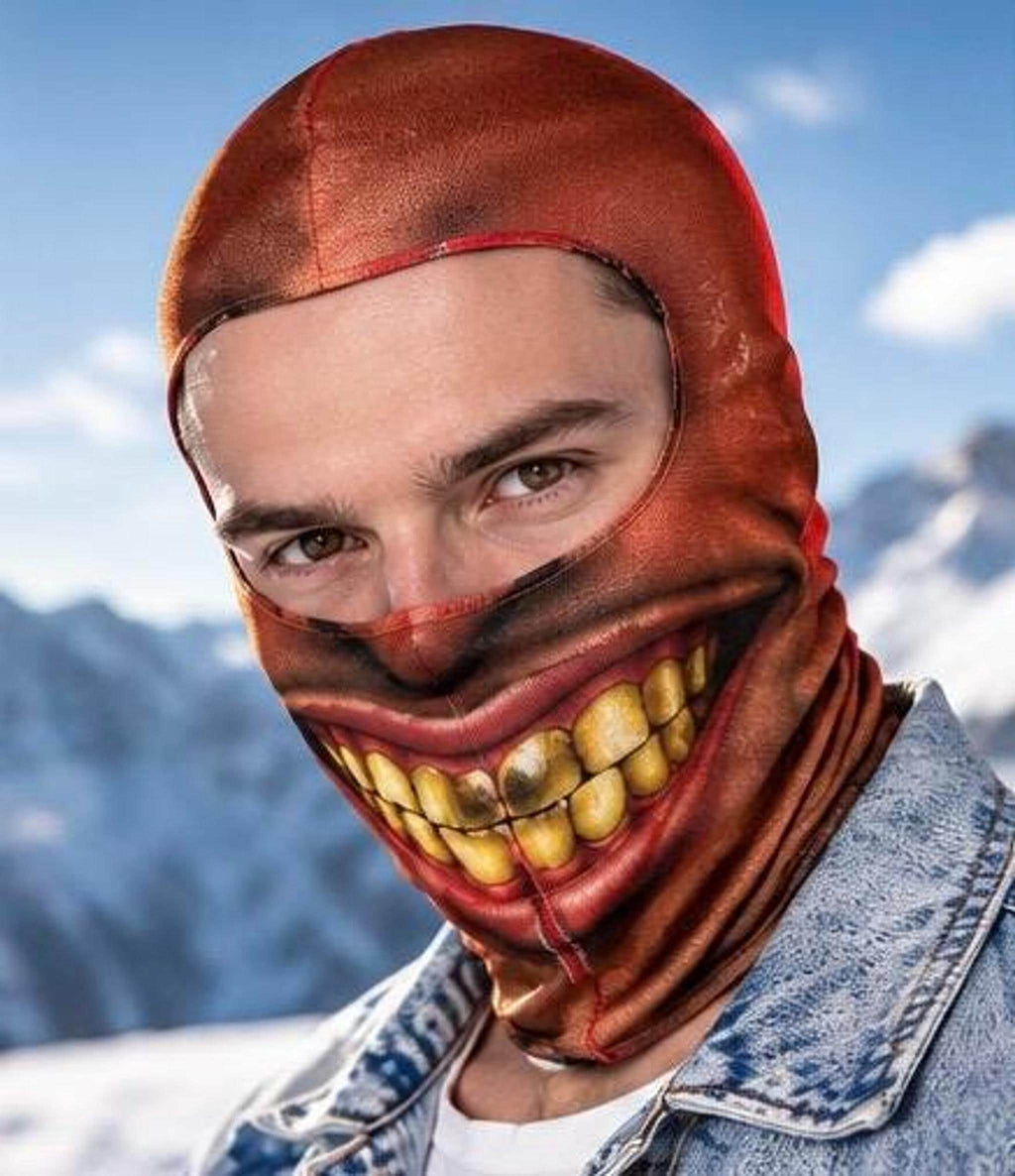 A portrait of a man wearing a balaclava with a creepy printed smile covering his lower face while leaving his eyes and forehead exposed against a snowy mountain backdrop.