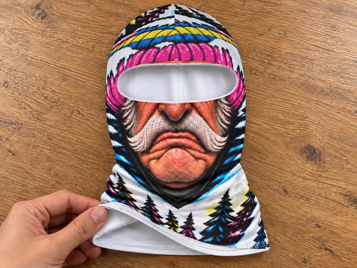 May include: A balaclava featuring a vibrant, full-color graphic print of an elderly person with a prominent white mustache and pink hat. The design includes a forest landscape with pine trees at the base and a white eye opening for visibility.